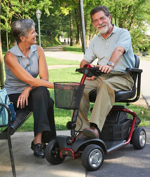 Senior man smiling on a red LiteRider 4-Wheel Mobility Scooter by Golden Technologies outdoors