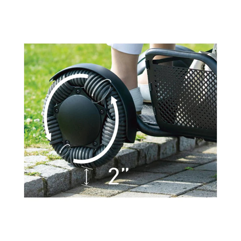 Close-up of WHILL Model C2 Smart Power Chair flexible wheel navigating a 2 inch curb outdoors